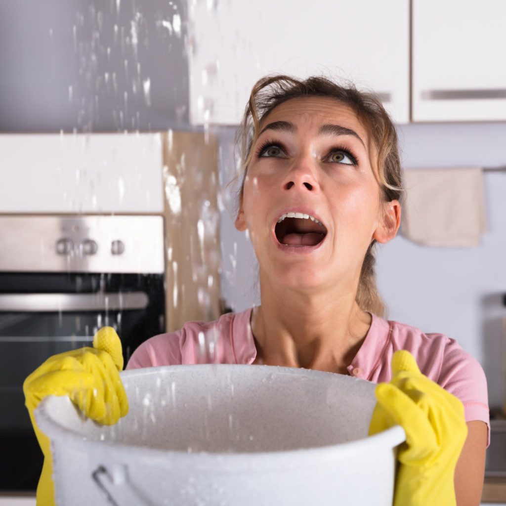 woman catching water leaking from the ceiling into a bucket